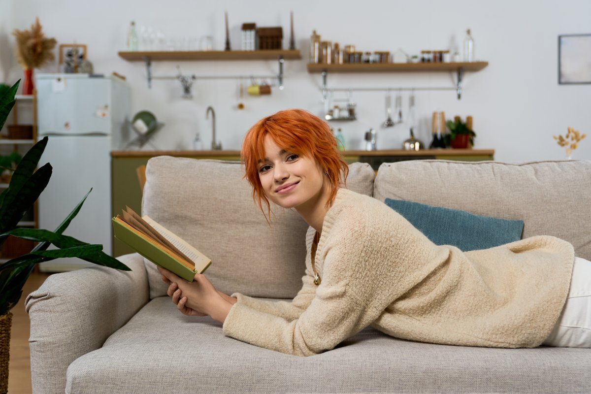 Smiling woman reading a book on the couch at home