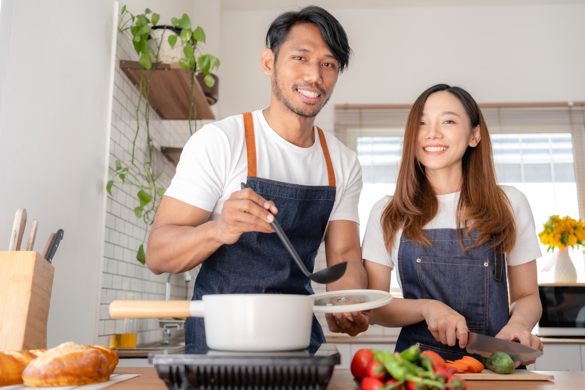 Happy couple cooking a pot of food together at home