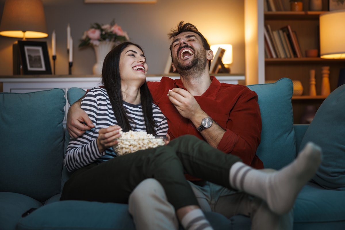 Stel lacht op de bank met popcorn tijdens een filmavond