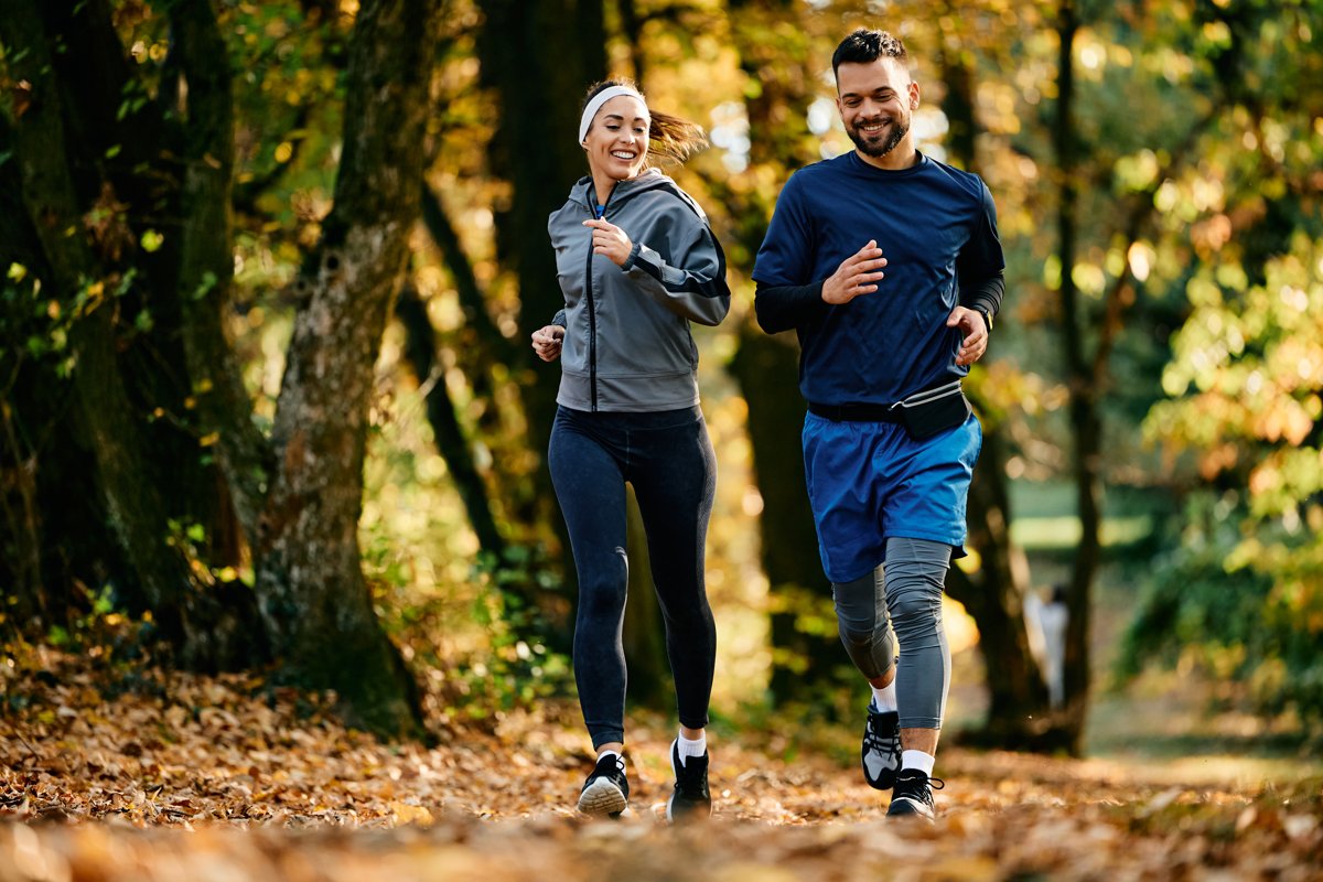 Blij stel loopt hard in het park in de herfst
