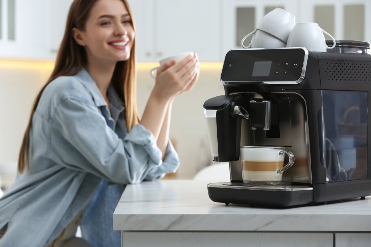 Vrouw geniet lachend van koffie naast een volautomaat