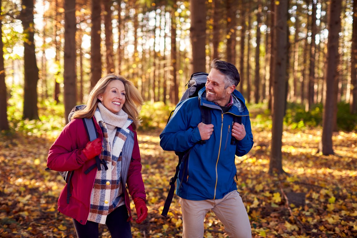 Paar wandert lachend durch einen Herbstwald