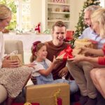 Smiling family opening gifts together on a sofa at home