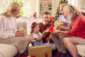 Smiling family opening gifts together on a sofa at home