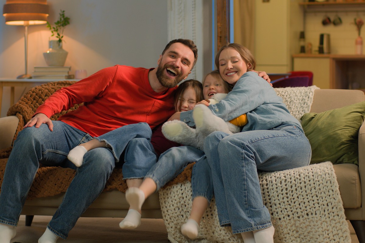 Family cuddling together on the living room sofa