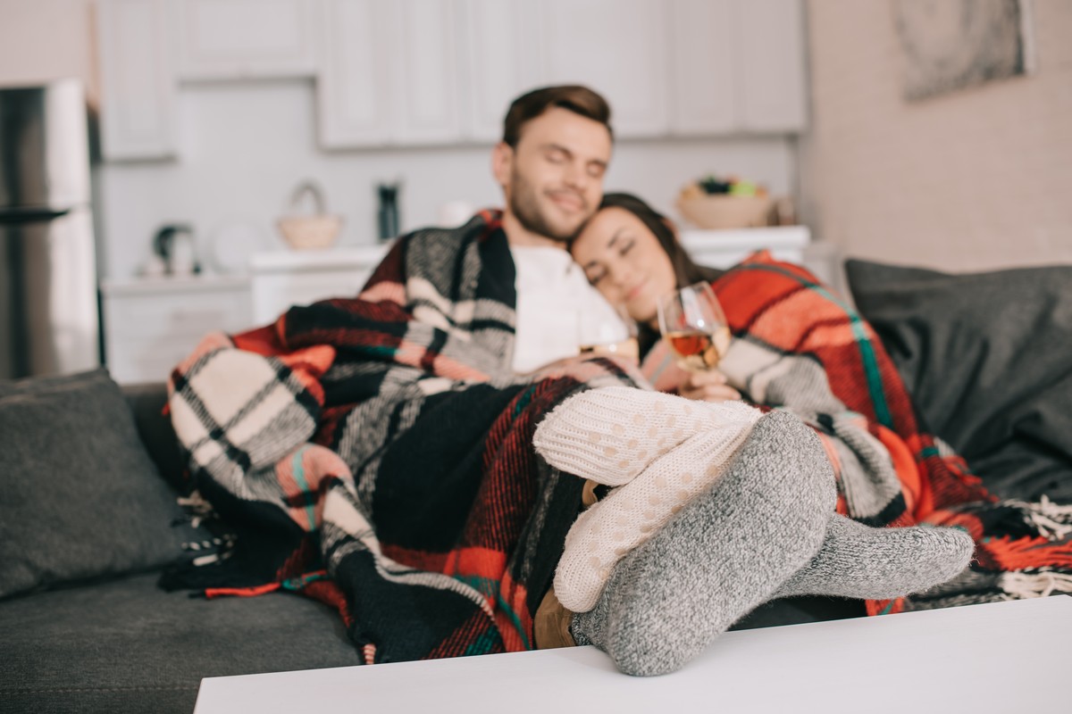 Couple relaxing on a sofa under a tartan blanket