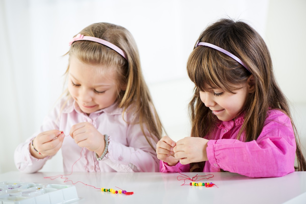Two girls making bead jewellery at a table