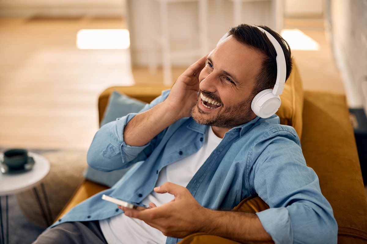 Man laughing while listening to music on white headphones