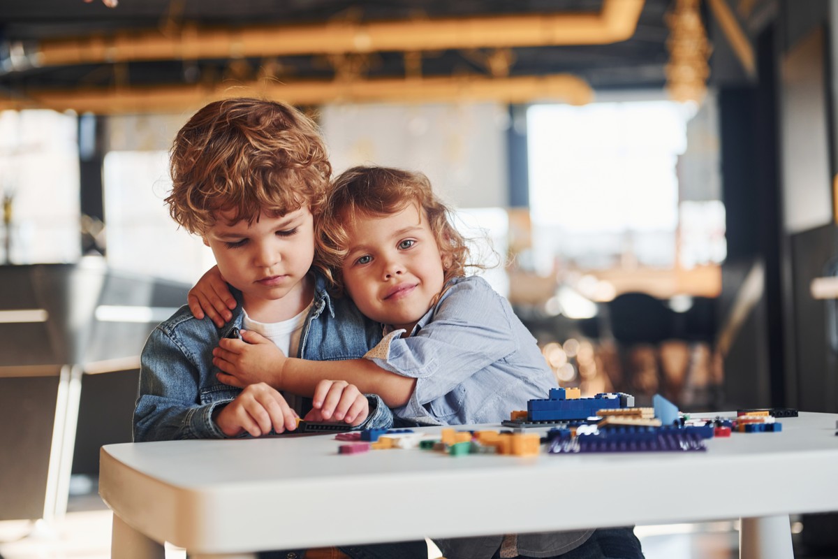 Two children playing with building bricks at a table