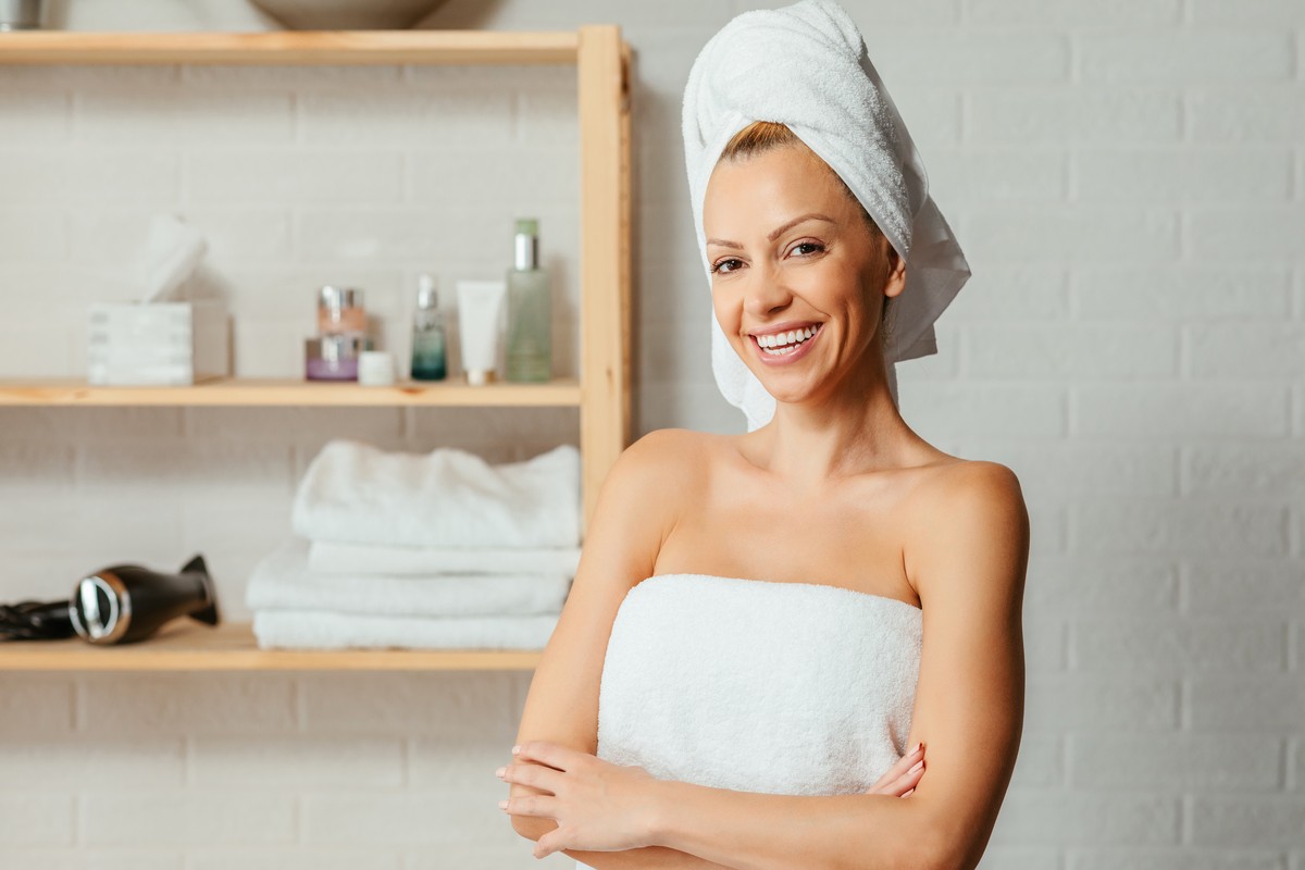 Smiling woman in a towel next to shelves of folded towels