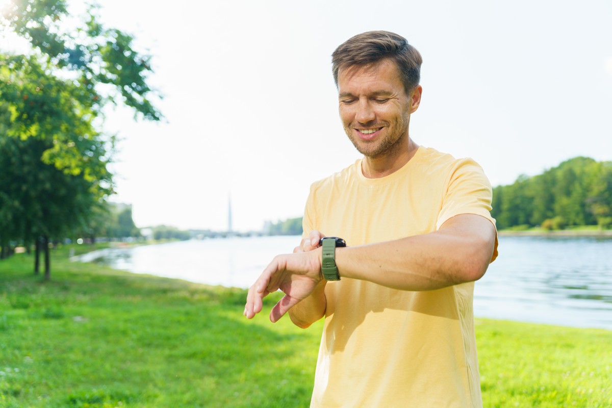 Smiling man checking his smartwatch in a park