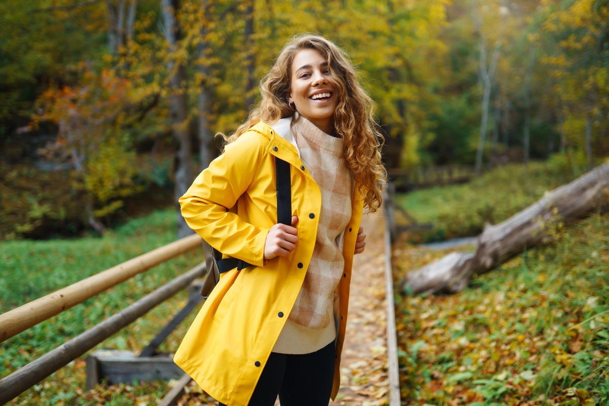 Femme souriante en ciré jaune dans un parc en automne