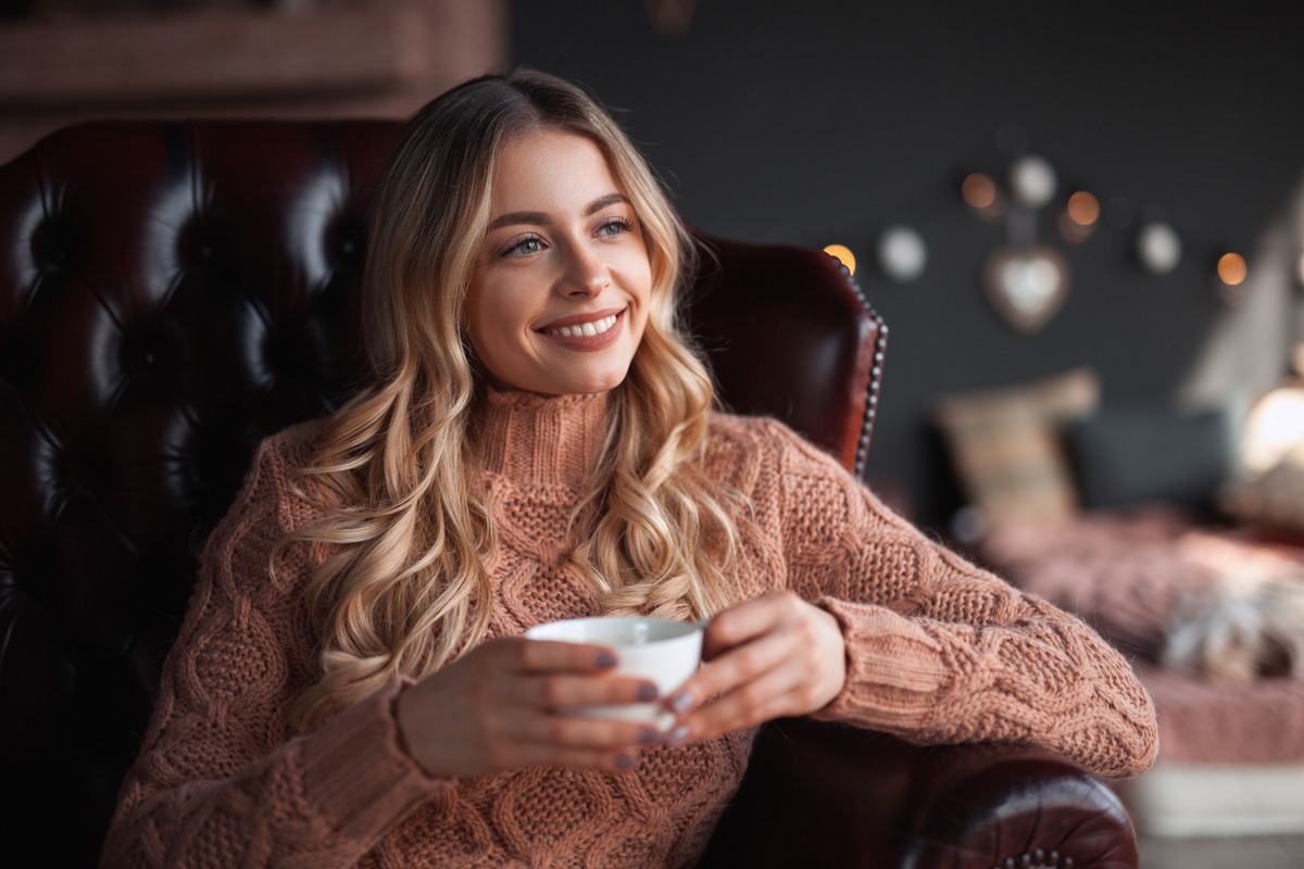 Femme souriante assise dans un fauteuil en cuir avec une tasse