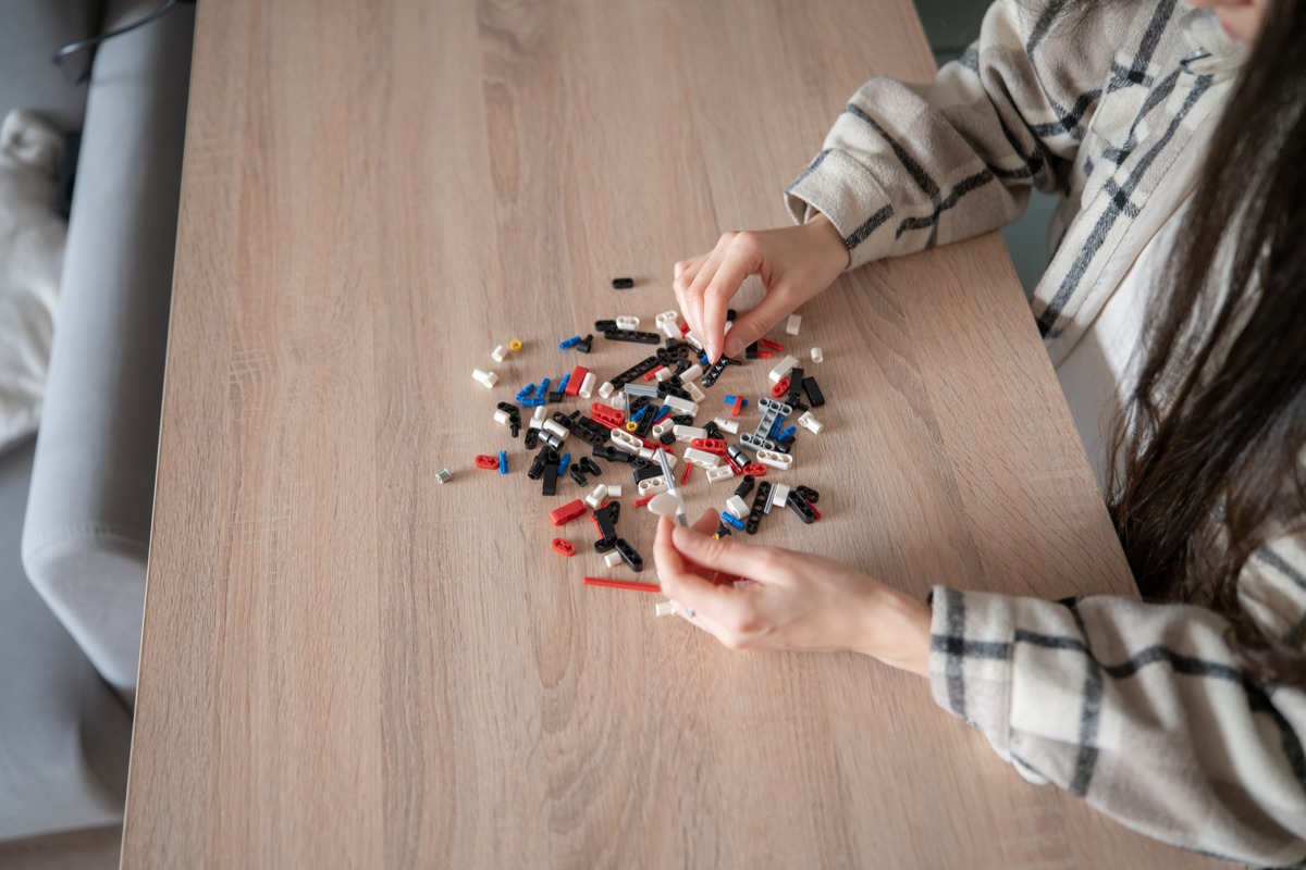 Mains qui assemblent des petites briques sur une table en bois