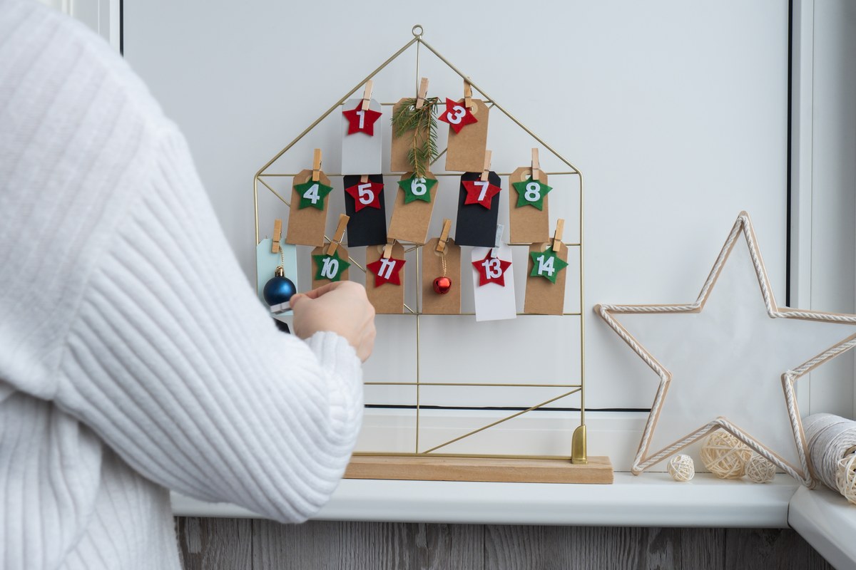 Calendrier de l’Avent à pochettes numérotées accroché sur un support doré