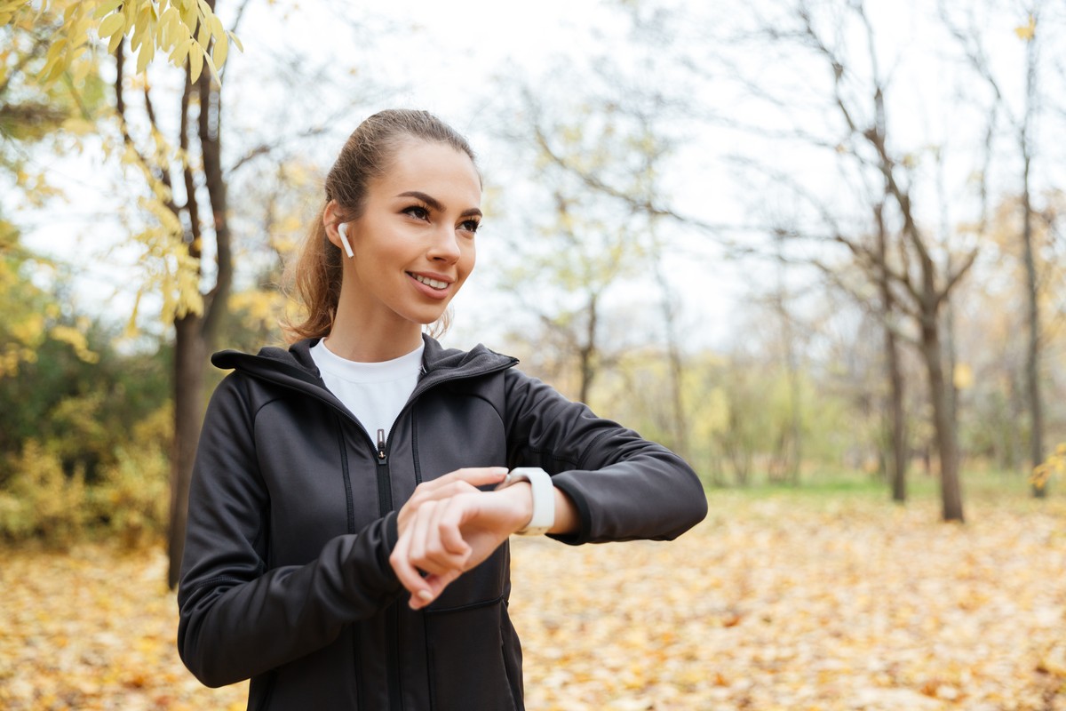 Vrouw bekijkt haar smartwatch tijdens een herfstwandeling in het park