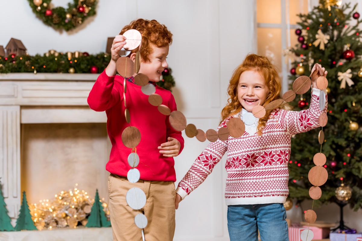 Twee lachende kinderen hangen een slinger op voor het feest