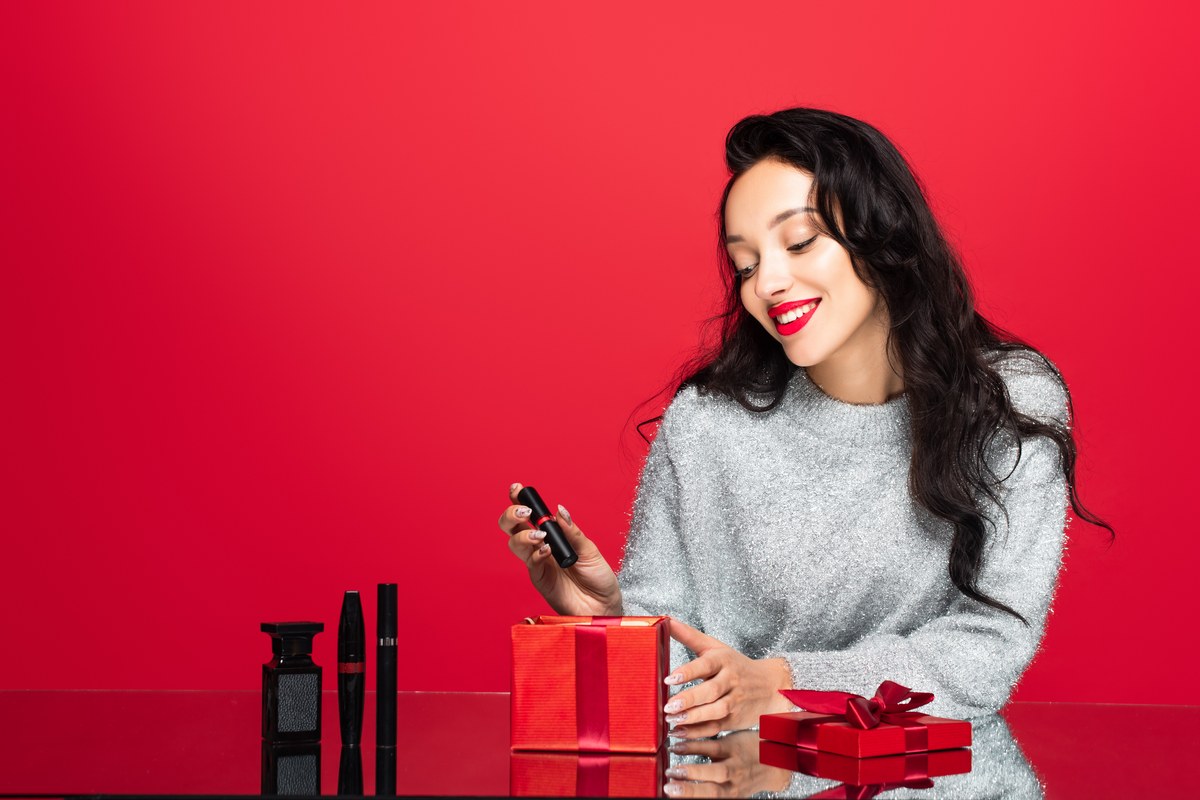 Smiling woman unwrapping a beauty gift set with red gift boxes