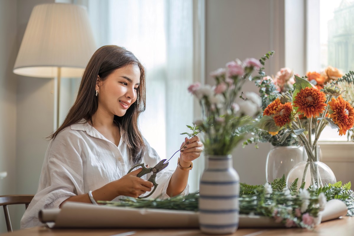 Woman arranging autumn flowers at a table at home