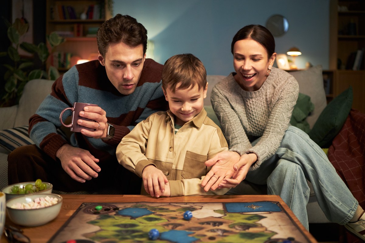 Family of three playing a board game on a coffee table at home