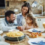 Smiling family of three sharing a meal at a kitchen table