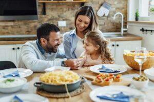 Smiling family of three sharing a meal at a kitchen table