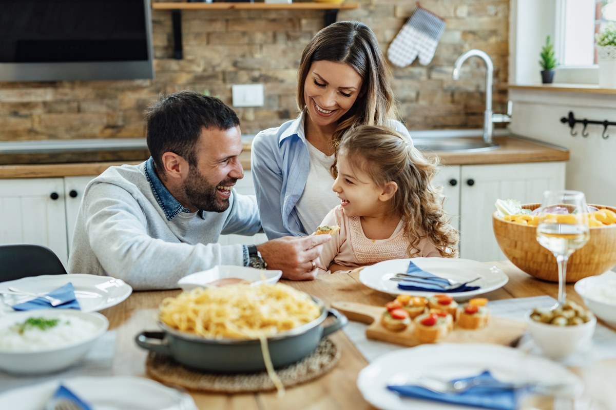 Smiling family of three sharing a meal at a kitchen table